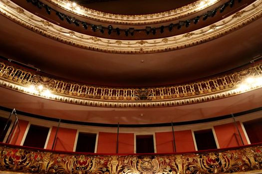 Richly decorated theater interior with gold details and dramatic lighting.